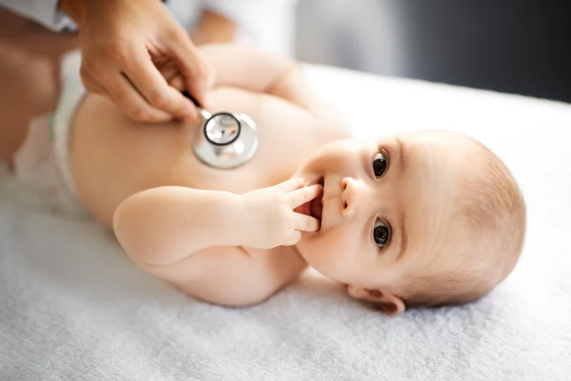 Atendimento especializado em neonatologia Bebê sorrindo enquanto um médico realiza exames com estetoscópio