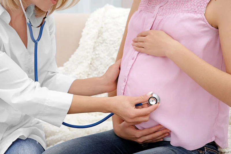 Cuidados obstétricos especializados para gestantes Médica examinando uma mulher grávida usando estetoscópio